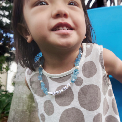 Little girl wearing blue aquamarine crystal necklace with WILD ONE bespoke beads